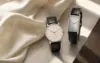 Unbranded round small-seconds watch and rectangular dress watch on ivory silk and travertine